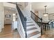 Grand staircase featuring hardwood steps and black wrought iron railing, with a view of the formal dining room at 10418 Pullengreen Dr, Charlotte, NC 28277