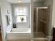 Bright bathroom featuring a soaking tub beneath a window and a glass-enclosed shower at 11511 Wilson Mill Ln, Pineville, NC 28134