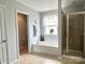 Bright bathroom featuring a soaking tub beneath a window and a glass-enclosed shower at 11511 Wilson Mill Ln, Pineville, NC 28134