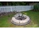 Backyard fire pit area with stone base, surrounded by green grass and a white picket fence at 1288 Shenandoah Cir, Rock Hill, SC 29730