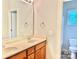 Bathroom featuring double sinks, framed mirror, wood cabinets, and a separate toilet area with window at 1302 Devonmere Pl, Salisbury, NC 28144