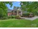 Elegant two-story brick home featuring a manicured lawn, classic columns, and beautiful landscaping at 1317 Longleaf Ct, Matthews, NC 28104