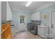Spacious laundry room features washer, dryer, basin and white cabinets at 1317 Longleaf Ct, Matthews, NC 28104