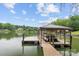 Covered boat dock features boat slip, with swim ladder; located on a calm lake surrounded by trees at 138 Ardmore Pl, Mooresville, NC 28117