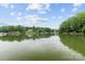 A scenic view of a calm lake with lush green trees in the background under a partially cloudy sky at 138 Ardmore Pl, Mooresville, NC 28117