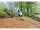 Backyard playground with a swing set, slide and playhouse, surrounded by trees and wood mulch at 138 Ardmore Pl, Mooresville, NC 28117