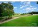 Lush green golf course with a winding path, trees, and a clear blue sky at 14746 Greenpoint Ln, Huntersville, NC 28078