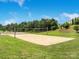 Sandy community volleyball court surrounded by green grass and trees under a sunny sky at 14746 Greenpoint Ln, Huntersville, NC 28078