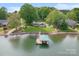 Aerial view of lakefront home with a boat dock, lush lawn, and mature trees at 173 Riverwood Rd, Mooresville, NC 28117