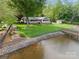 View of the backyard with lush lawn, mature trees, and dock leading to the water at 173 Riverwood Rd, Mooresville, NC 28117