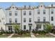 Charming exterior of a three-story white brick townhouse with manicured landscaping and a black iron fence at 4148 Alexander View Dr, Charlotte, NC 28226