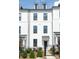 Elegant townhome with white brick, black framed windows, and iron gate fence and mature landscaping at 4148 Alexander View Dr, Charlotte, NC 28226