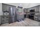 Rustic kitchen with gray cabinets, stainless steel appliances, brick backsplash, and hardwood flooring at 4592 Reid Rd, Edgemoor, SC 29712