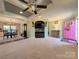 Open-concept living room showcasing a decorative ceiling fan, a pink front door, and neutral carpet at 4713 White Store Rd, Wingate, NC 28174