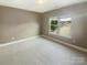 Bedroom with neutral walls and carpet; a bright window looks out onto green lawns and homes at 5003 Tremont Dr, Indian Trail, NC 28079