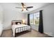 Bright bedroom with a metal bed frame, a ceiling fan, and a window offering neighborhood views at 5069 Thomasville Dr, Belmont, NC 28012