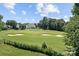 A well-manicured golf course with sand traps and a beautiful home in the background at 615 N Oak Dr, Huntersville, NC 28078