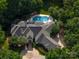 Stunning aerial view of the luxury home with mature trees surrounding a backyard pool area at 7912 Baltusrol Ln, Charlotte, NC 28210
