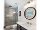 Modern bathroom featuring a tiled shower, sink with navy blue cabinet, and round mirror at 8310 Brickle Ln, Huntersville, NC 28078