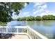 Scenic view of the lake from a wooden deck with a white railing and partial shade at 9808 Steed Ct, Charlotte, NC 28269