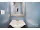 Quaint powder room featuring a pedestal sink, framed mirror, and light blue walls at 9808 Steed Ct, Charlotte, NC 28269