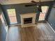 Bright living room featuring fireplace, two windows, ceiling fan, and hardwood floor at 11021 Scrimshaw Ln, Charlotte, NC 28215