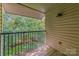 Private outdoor balcony with wood flooring, railing, and serene views of mature trees at 11049 Cedar View Rd, Charlotte, NC 28226
