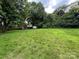 Expansive backyard featuring lush green grass, mature trees, a wooden fence and storage sheds at 111 Rose St, Mount Holly, NC 28120