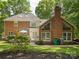 Brick home featuring mature landscaping, large windows, and rear patio at 1140 Iverleigh Trl, Charlotte, NC 28270