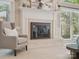 Close up of cozy fireplace, featuring large windows, comfortable armchair, and mantel decor at 1140 Iverleigh Trl, Charlotte, NC 28270