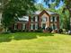 Stunning brick home with a large lawn, mature trees, and classic black shutters at 1140 Iverleigh Trl, Charlotte, NC 28270