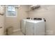 Bright laundry room features white washer and dryer, overhead shelving, and tile flooring at 135 Asmodean Ln, Troutman, NC 28166