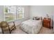 Well-lit bedroom featuring a window and charming rocking chair with hardwood side table at 1391 Links Crossing Dr, Monroe, NC 28112