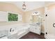 Bright bathroom showcasing garden tub with tile surround, and window with view of lush landscaping at 1545 Chadmore Nw Ln, Concord, NC 28027
