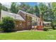 Back exterior of a brick home with a large yard and deck surrounded by mature trees at 1545 Chadmore Nw Ln, Concord, NC 28027