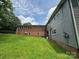 A view of the backyard, showcasing the home's brick and gray siding and a slightly sloping green lawn at 2116 Dana Pl, Shelby, NC 28152