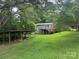 Expansive backyard with wooden carport, deck, and home exterior visible among mature trees at 2116 Dana Pl, Shelby, NC 28152