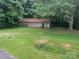 Rustic outbuilding with a weathered wooden exterior, nestled in a grassy yard surrounded by trees at 2116 Dana Pl, Shelby, NC 28152