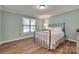 Light blue bedroom features a window, ceiling fan and a queen-sized bed with wood-look flooring at 353 Tall Oaks Trl, Fort Mill, SC 29715
