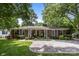 Charming brick home with a manicured lawn, concrete driveway, and a welcoming front porch with seating at 5640 Sharon Rd, Charlotte, NC 28210