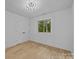 Bright bedroom features a modern light fixture, window, and hardwood floors at 6501 Piney Path Rd, Charlotte, NC 28212