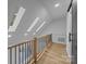 Well-lit upper hallway featuring skylights, wood floors, and a view down to the living area below at 6501 Piney Path Rd, Charlotte, NC 28212