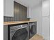 Contemporary laundry room featuring a butcher block countertop, black front-load washer and dryer, and stylish tiling at 6501 Piney Path Rd, Charlotte, NC 28212
