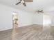 Wood-look floors extend into this empty room with two ceiling fans, with a view into the kitchen at 7416 Quail Ridge Dr, Charlotte, NC 28226