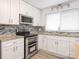 Well-lit kitchen features white cabinets, stainless steel appliances, granite countertops, and stylish backsplash at 7416 Quail Ridge Dr, Charlotte, NC 28226