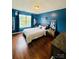 This cozy bedroom features rich blue walls, a window for natural light, and wood flooring throughout at 7918 Boars Head Ct, Charlotte, NC 28214