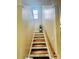 Ascend the staircase with wooden treads and a handrail, illuminated by a natural light window, creating a warm ambiance at 7918 Boars Head Ct, Charlotte, NC 28214
