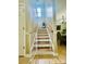 This naturally lit staircase features wooden steps, a safety gate and a window at the top with a glimpse of the dining room at 7918 Boars Head Ct, Charlotte, NC 28214