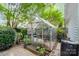 Exterior shot of a charming greenhouse next to the main house, surrounded by greenery at 9011 Brad Ct, Matthews, NC 28104