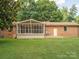 Home exterior featuring a spacious backyard with a wooden deck and screened in back porch at 10728 Forest Dr, Matthews, NC 28105